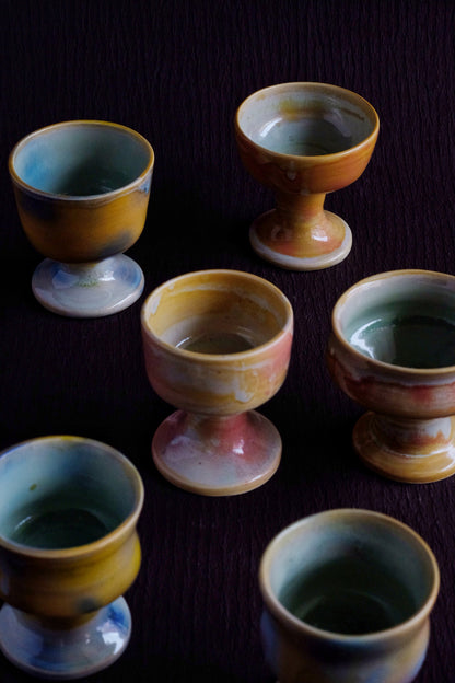 Set of ceramic egg cups with a multicolored glaze on a dark surface